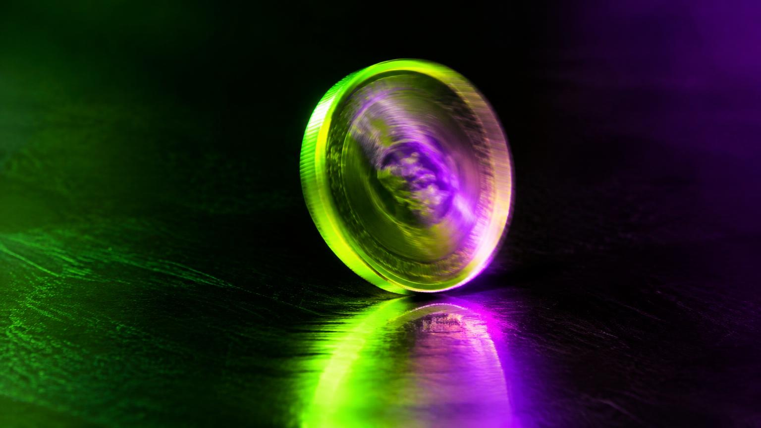 Moeda girando sob luz neon verde e roxa